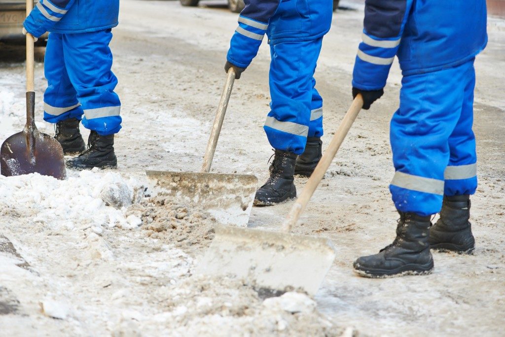 municipal urban servicing workers shoveling snow during winter road cleaning 
