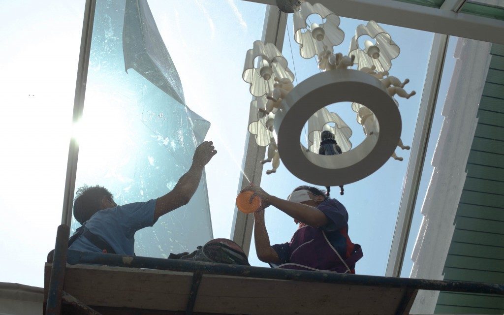 unidentified people wrappers tinting a glass house window with a tinted foil or film using foggy spray