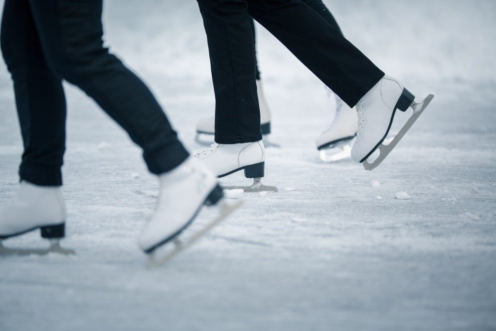 Motion blurred feet of people ice skating outdoors on a pond on a freezing winter day 