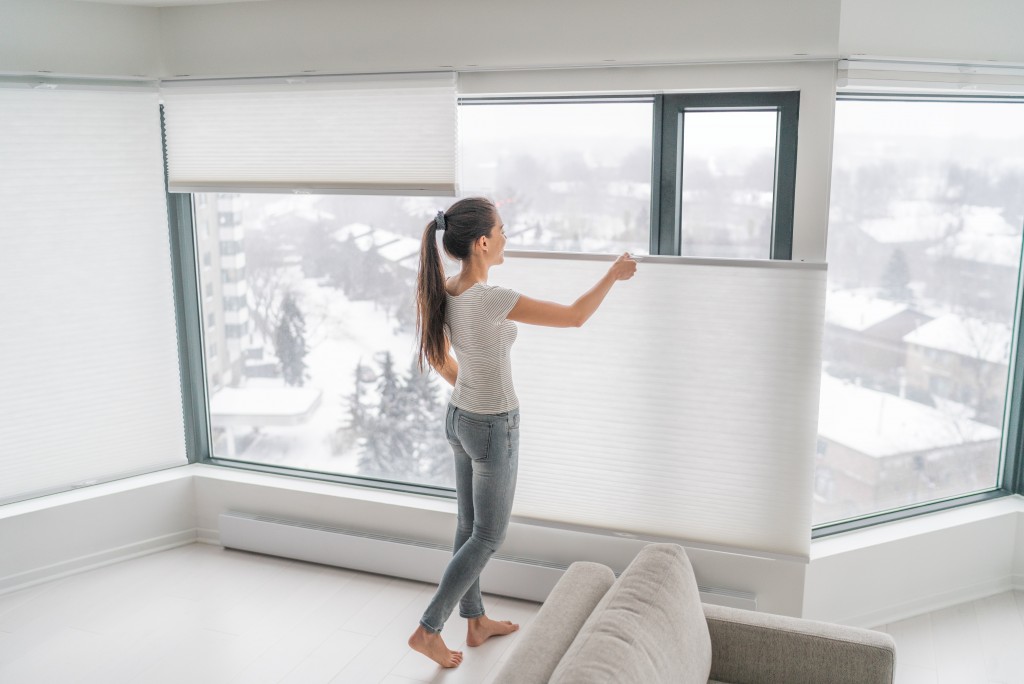 woman adjusting her window blinds