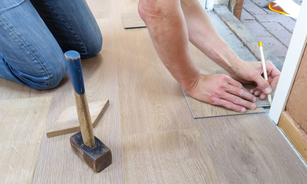 person measuring a tile on the floor