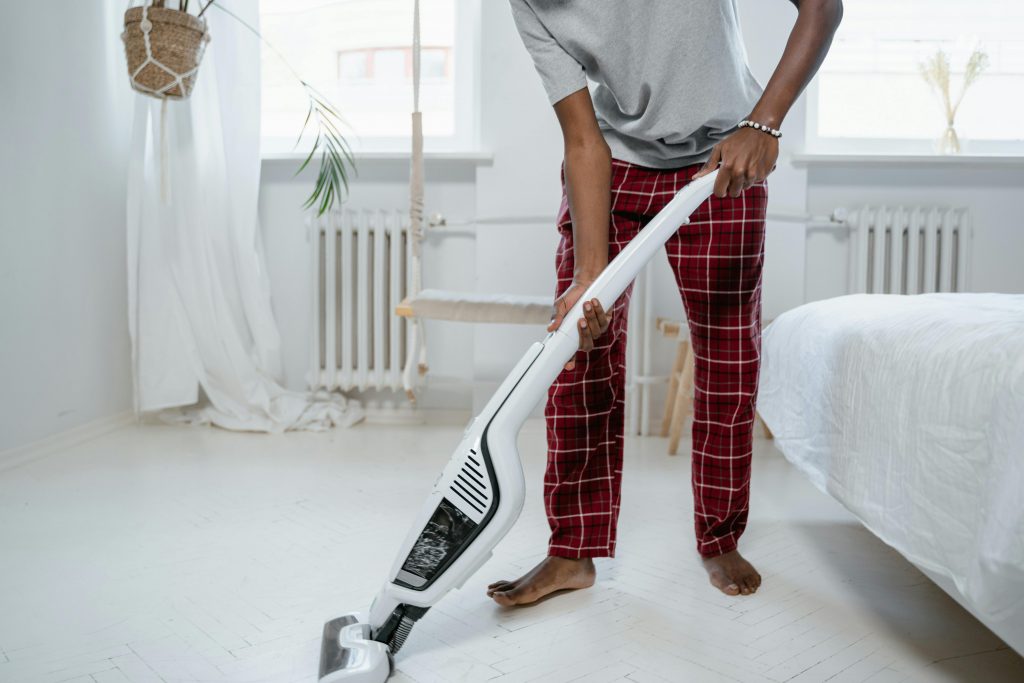 man vacuuming the floor of a bedroom
