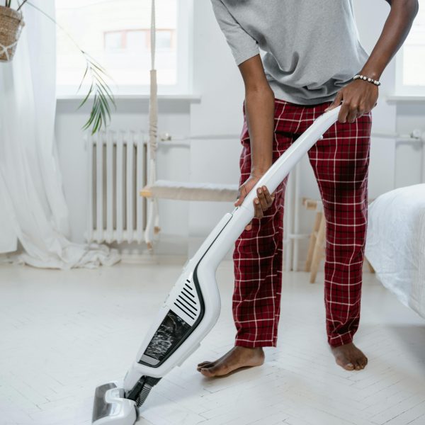 man vacuuming the floor of a bedroom