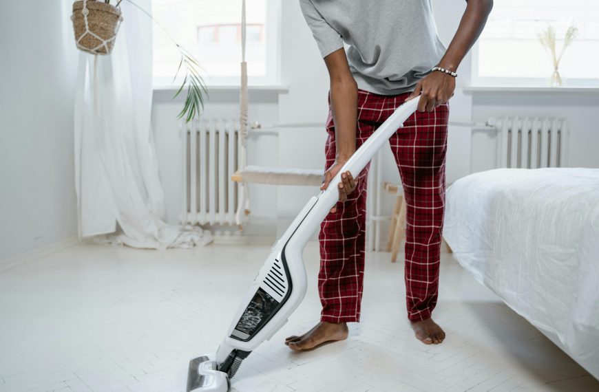 man vacuuming the floor of a bedroom